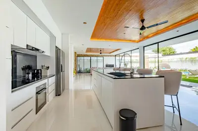 a kitchen with white cabinets and a wooden ceiling at Villa Kamawis Seminyak in Seminyak