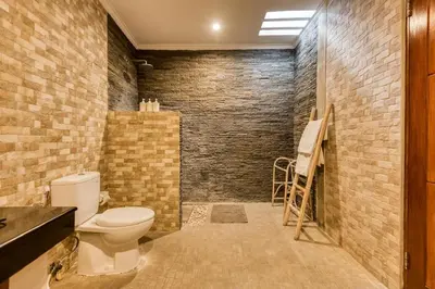 a bathroom with a toilet and a brick wall at Dion Villas Berawa only 5 Minutes by scooter to Finns beach club in Canggu