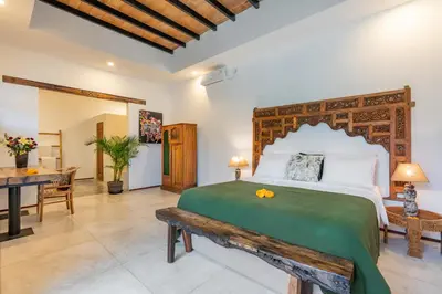 a bedroom with a large bed and a desk at Villa Wuizy By DreamAwayBali in Seminyak