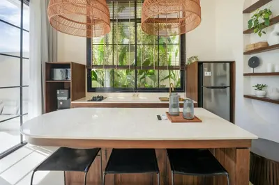 a kitchen with a table with chairs and two lights at Villa Benteke Umalas in Kerobokan