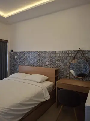 a bedroom with a bed and a desk and a mirror at Ayoolasudi in Kerobokan