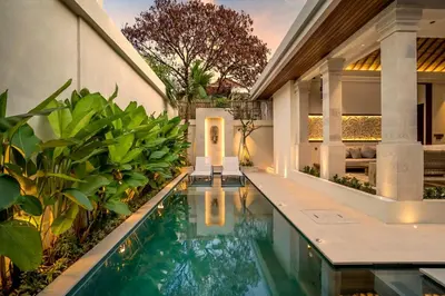 a swimming pool in front of a house with plants at Villa Advaya by Maheswara in Seminyak