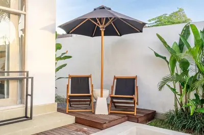 two chairs and an umbrella on a porch at La Palma - Spacious 2BR Villa with Large Pool in Canggu in Canggu