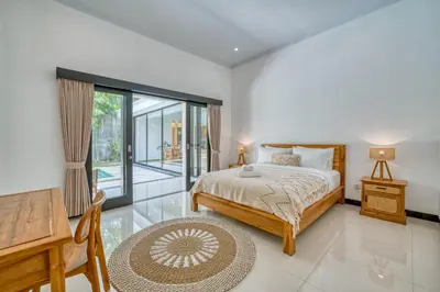 a bedroom with a bed and a desk and a window at Villa D Canggu in Canggu