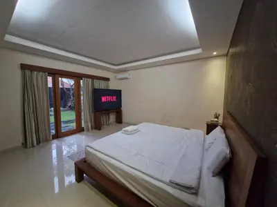 a bedroom with a bed and a tv in it at Max Guest House in Seminyak