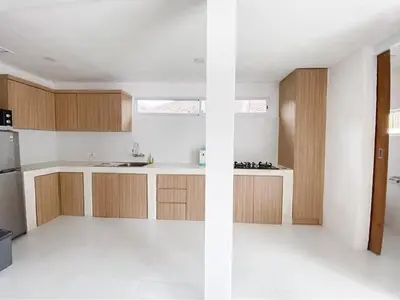a kitchen with white counters and wooden cabinets at The Pink Door Villa in Legian