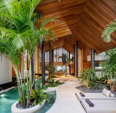 an indoor courtyard with palm trees and a pool at House of Winds Complex - Luxury 6BR Tropical Retreat - 2x3BR Villas near Canggu in Kerobokan