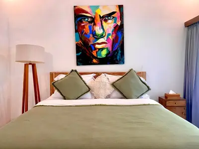 a bedroom with a bed with a painting on the wall at Villa Pastis Umalas #2, near Canggu in Canggu