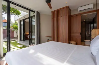 a bedroom with a large white bed and sliding glass doors at Solencia Villa by Betterplace in Jimbaran
