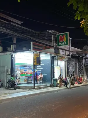 a group of people sitting outside of a market at night at Cozy room Kuta - 1 minutes to the beach by Micky Studio2 in Legian