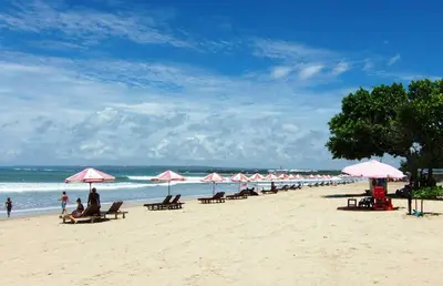 a beach with umbrellas and people sitting on the beach at Cozy room Kuta - 1 minutes to the beach by Micky Studio2 in Legian