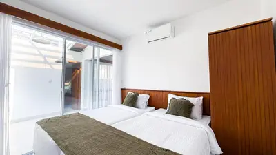 a bedroom with two beds and a large window at Casa De Vero Amore in Jimbaran