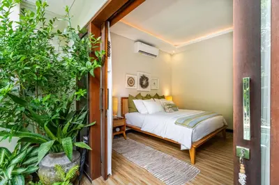 a bedroom with a bed and some plants at Tropical 2BR Villa with Private Pool in Canggu in Canggu