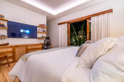 a bedroom with a large white bed and a flat screen tv at Tropical 2BR Villa with Private Pool in Canggu in Canggu