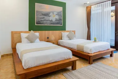 two beds in a room with green and white at Purnava Village by Behomy in Ngurah Rai International Airport