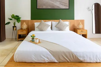 a bedroom with a large white bed with two tables at Purnava Village by Behomy in Ngurah Rai International Airport