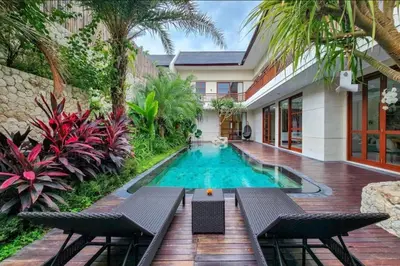 a swimming pool in front of a house at Elf Belly 4 BR Canggu Heart Vila CYN in Canggu