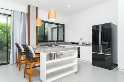 a kitchen with a counter with chairs and a sink at Villa Damai Canggu in Seminyak
