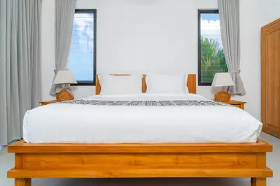 a bedroom with a large white bed with two windows at Villa Damai Canggu in Seminyak