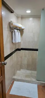 a bathroom with a shower with white towels at The Palmana Tropical Roofline Jayakarta Residence 40 in Badung