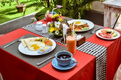 a table with breakfast foods and a cup of coffee at Palm Garden Bali in Nusa Dua