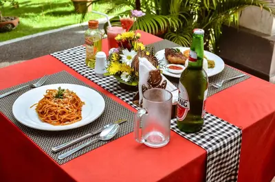a table with plates of pasta and a bottle of beer at Palm Garden Bali in Nusa Dua