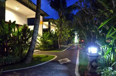 a street with palm trees and a building with a car at Palm Garden Bali in Nusa Dua