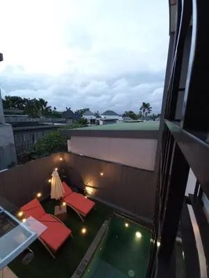a balcony with red chairs and a table and a pool at PalmA Private Villa - A Leafy Place in Mumbul Hill in Nusa Dua