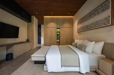 a bedroom with a large white bed and a flat screen tv at Marvee Suites Bali in Canggu