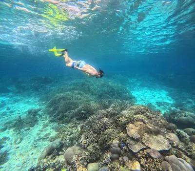 a man swimming over a coral reef in the ocean at Круиз на Яхте с Бали на Нуса Пенида in Sanur