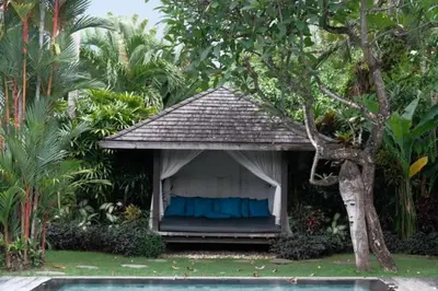 a small house with a blue curtain in a yard at Bali paradise Rosa in Seminyak