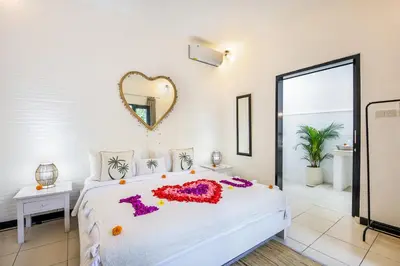 a bedroom with a large bed with a heart mirror on the wall at Villa Mandari in Seminyak