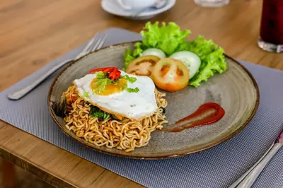 a plate of food with noodles and vegetables on a table at Villa Mandari in Seminyak