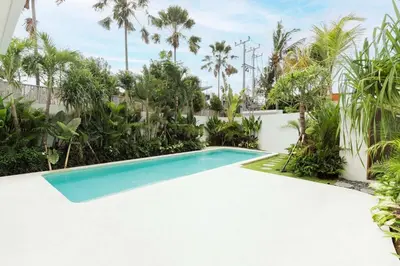 a swimming pool in a backyard with palm trees at Elegant 4BR Villa downtown Berawa Canggu in Canggu
