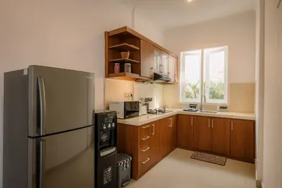 a kitchen with a stainless steel refrigerator and wooden cabinets at Villa Batu Putih 3 Seminyak in Seminyak