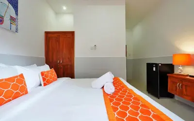 a bedroom with a bed with orange and white pillows at Kamar Kodel1 in Seminyak