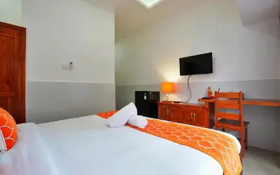 a bedroom with a bed and a desk with a television at Kamar Kodel1 in Seminyak