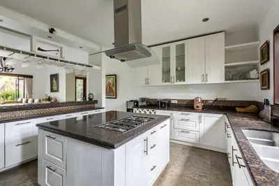 a kitchen with white cabinets and black counter tops at 5 Bedroom Luxury Villa With Huge Garden & Pool 150-Metres To Seminyak Beach in Seminyak