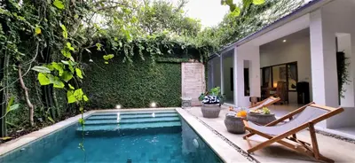 an outdoor swimming pool with a chair and a house at Tropical 2br private pool Villa in central Seminyak in Seminyak