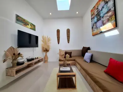 a living room with a couch and a tv at Villa A La Cool Seminyak in Seminyak