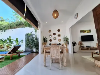 an open living room with a wooden table and chairs at Villa A La Cool Seminyak in Seminyak