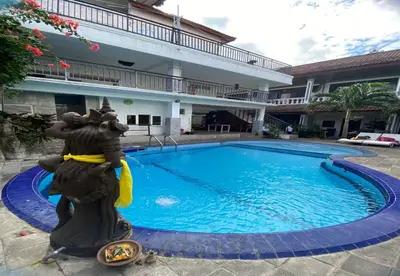 a swimming pool with a statue next to a building at Hotel Near Beach Ayu inn Kuta in Kuta
