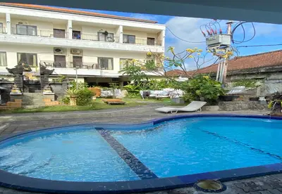a large blue swimming pool in front of a building at Hotel Near Beach Ayu inn Kuta in Kuta