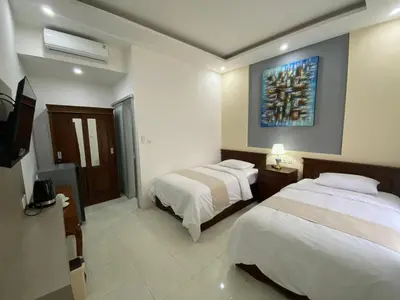 a hotel room with two beds and a tv at Bidadari Homestay Nusa Dua in Nusa Dua