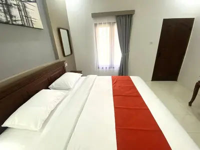 a bedroom with a bed with a red and white blanket at Bidadari Homestay Nusa Dua in Nusa Dua
