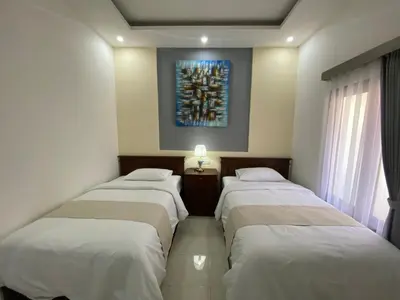 three beds in a room with a painting on the wall at Bidadari Homestay Nusa Dua in Nusa Dua
