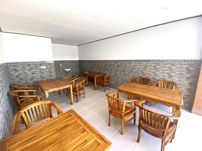 a restaurant with wooden tables and chairs at Bidadari Homestay Nusa Dua in Nusa Dua