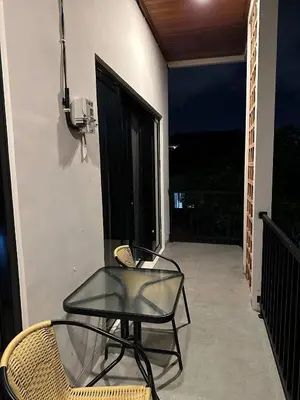 a glass table and chair on a balcony at night at Kubu Gandi Homestay in Denpasar