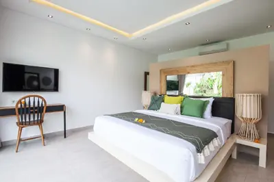 a bedroom with a bed and a desk and a tv at Villa Hugo in Canggu