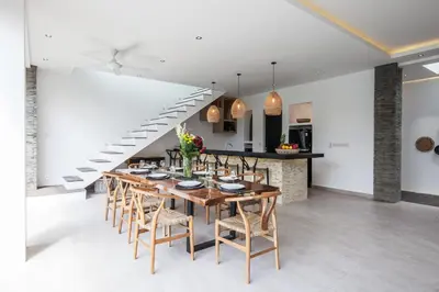a dining room with a table and chairs and a staircase at Villa Hugo in Canggu